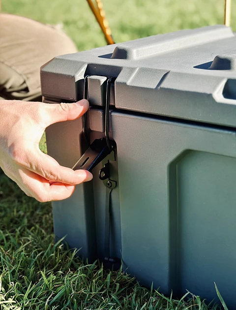 Close-up of a hand securing the latch on a heavy-duty poly cargo box